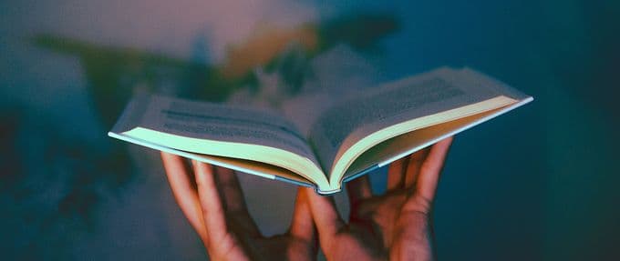 photo of hands holding a book up in the air