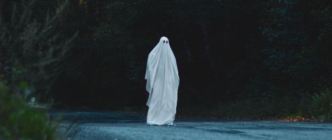 A sheet ghost standing in the road.