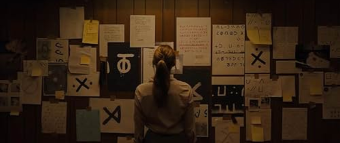 A woman standing in front of papers with foreign writing on the wall. 